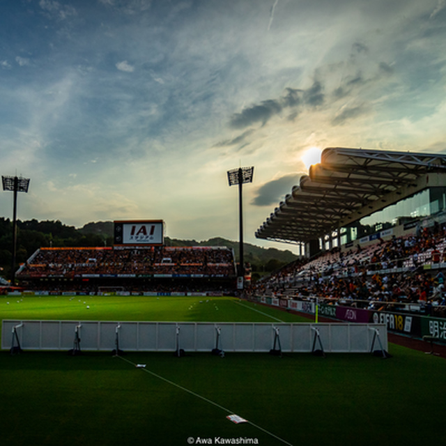 沈みゆく夕陽とキックオフを待つスタジアム情景